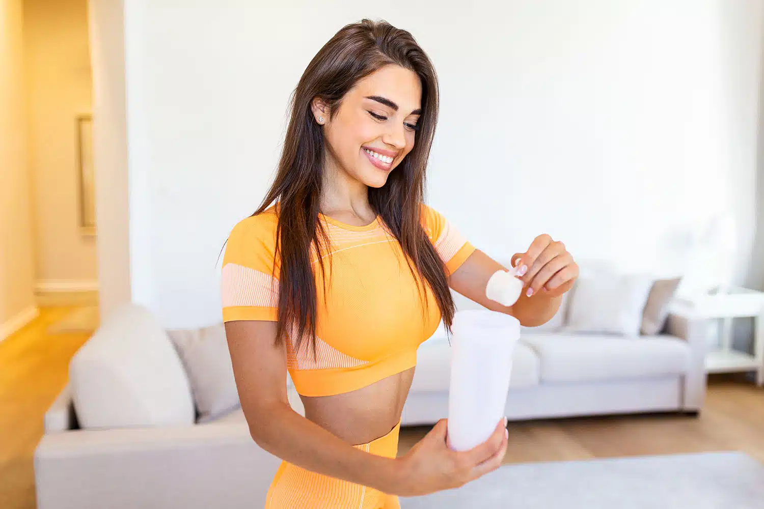 Benefits of Creatine for Women a woman holding a shaker bottle putting in a scoop of Creatine to represent "Benefits of Creatine for Women"